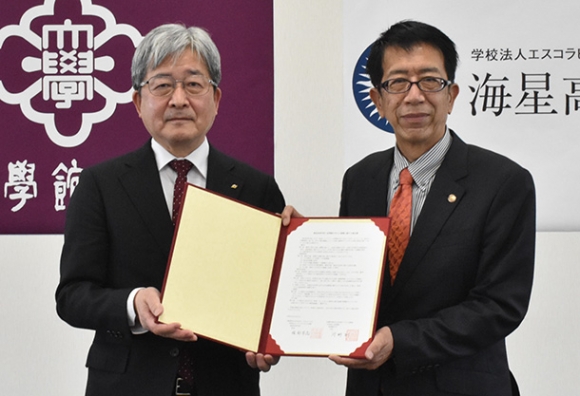 協定書を手にする皇学館大の河野学長(左)と海星高の服部校長=伊勢市の皇学館大で