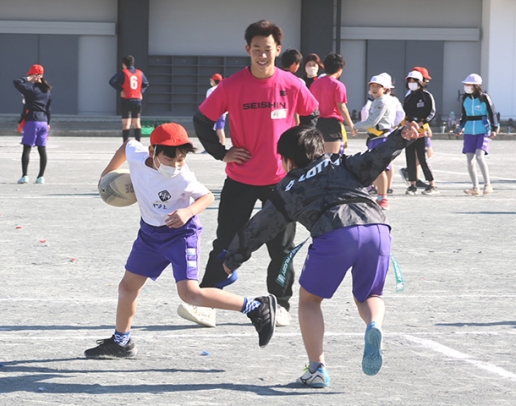 誠信高生の指導でタグラグビーを楽しむ児童たち＝扶桑町の扶桑東小で