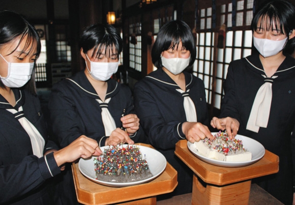 授業で使った針をこんにゃくと豆腐に刺す生徒たち=一宮市の真清田神社で