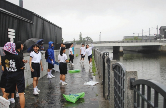 元気よく半田運河にEMダンゴを投げ入れる生徒たち=半田市の半田運河で