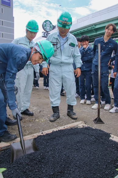 アスファルトをならす作業を体験する生徒ら=昭和区白金3で