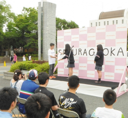 ピースリレーの出発式でたすきを受け取る第1陣の生徒=豊橋市南牛川の桜丘高で