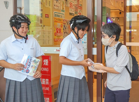 買い物客に啓発グッズを手渡す生徒=高山市岡本町で