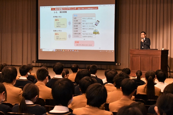 家計管理について説明する村城さん＝津市の高田高で