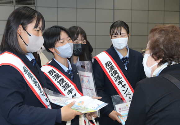 通行人に啓発グッズを手渡す高校生＝ＪＲ名古屋駅前で