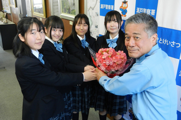内田署長（右端）にベゴニアを手渡す聖カピタニオ女子高の生徒たち＝瀬戸署で