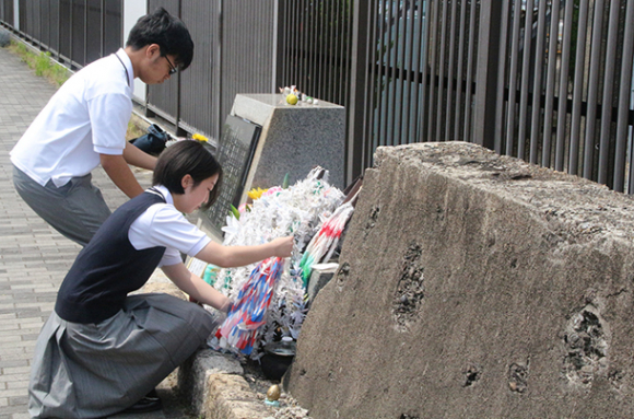 記念碑に折り鶴などを手向ける中京大付属中京高の生徒＝熱田区千年１で