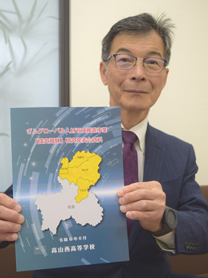 生徒らの研究をまとめた冊子を紹介する小林校長＝中日新聞高山支局で