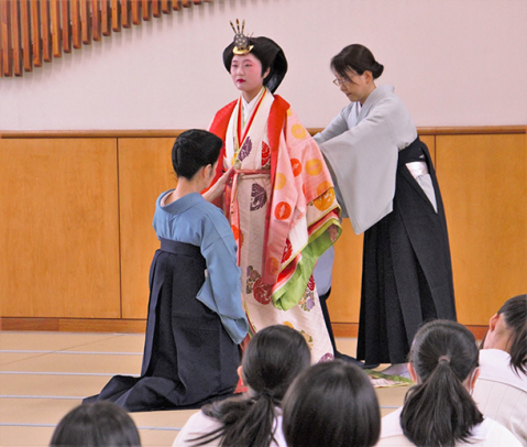川崎さんらに十二単を着付けてもらっている三橋さん＝豊橋市老松町の藤ノ花女子高で
