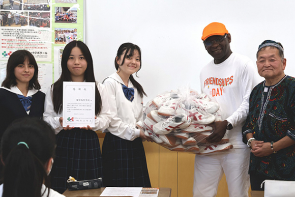 生徒から体育館シューズを受け取るカクさん（右から２人目）＝岐阜市野一色の富田高で