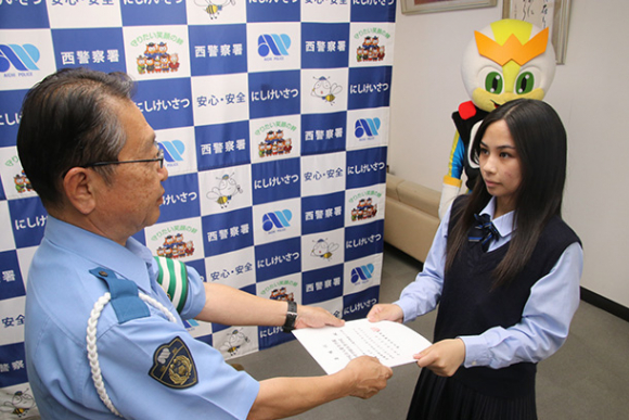  萩原署長（左）から委嘱状を受け取る生徒＝西署で