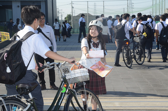 ヘルメットをかぶって登校する生徒にちらしを配る生徒会関係者＝愛西市の清林館高で