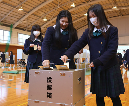 投票箱に票を投じる生徒たち＝四日市市の暁中学校・高校で