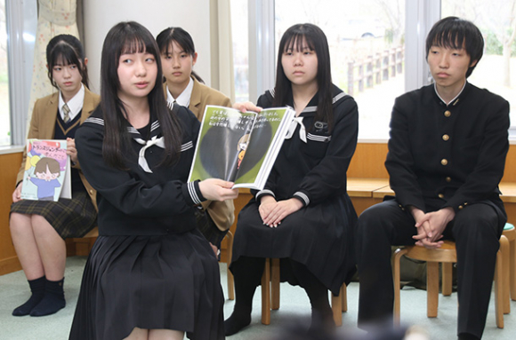 絵本を読み聞かせる生徒（手前）ら＝菰野町図書館で