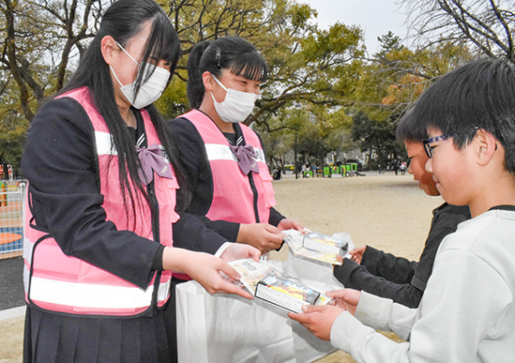 子どもの広場で来園者に防犯ブザーなどを配る桜花学園高インターアクトクラブの部員たち＝昭和区の鶴舞公園で