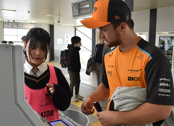 ＩＣカードへのチャージ方法を教える高田高の生徒（左）＝鈴鹿市の近鉄白子駅で