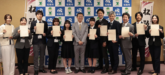 竹上市長（左から６人目）から委嘱状を受けたアナウンサーのみなさん＝松阪市役所で