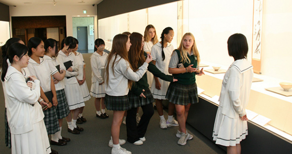 展示室を見て回るセントヨゼフ女子学園高生徒と留学生ら＝津市垂水の石水博物館で