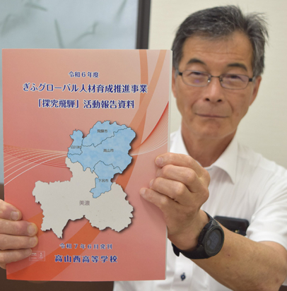地域にまつわる生徒の研究をまとめた冊子を紹介する小林理事長＝中日新聞高山支局で