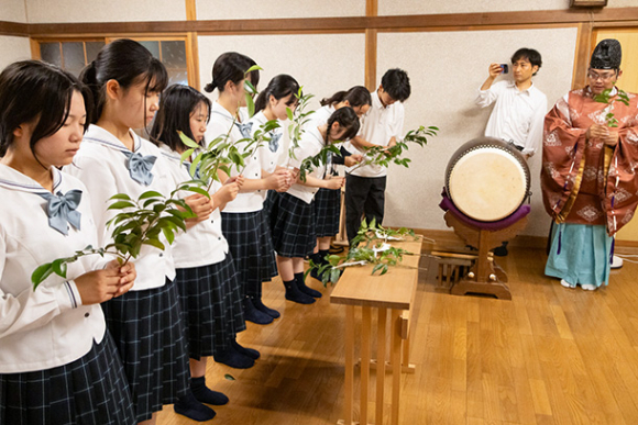 玉串奉奠の作法を学ぶ愛知啓成高の生徒たち＝犬山市栗栖の桃太郎神社で