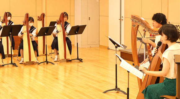 ハープアンサンブル部の部員に指導するハープ奏者の上原さん(右)とフィドル奏者の小松さん(右から2人目)=東区の金城学院高で