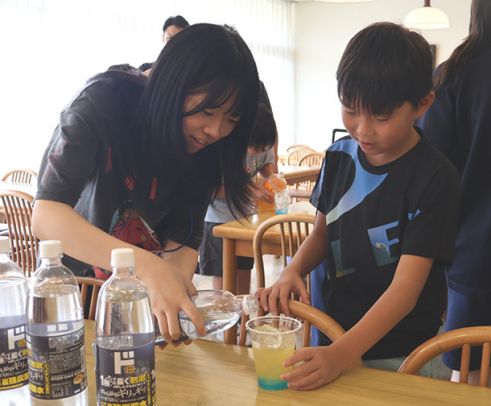 児童を手伝う通信制の生徒ボランティア（左）＝四日市市の四日市メリノール学院で