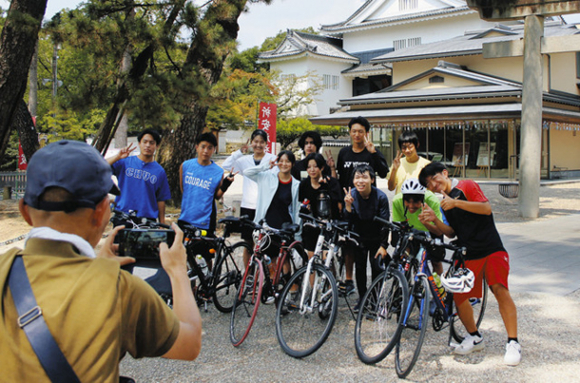 岡崎城の前で記念撮影する豊橋中央高の自転車ピースリレーのメンバーら＝岡崎市で
