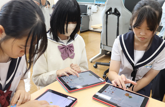 オープンスクールに参加し、桜花学園高の生徒（中）とともに設計を体験する中学生＝昭和区の同校で