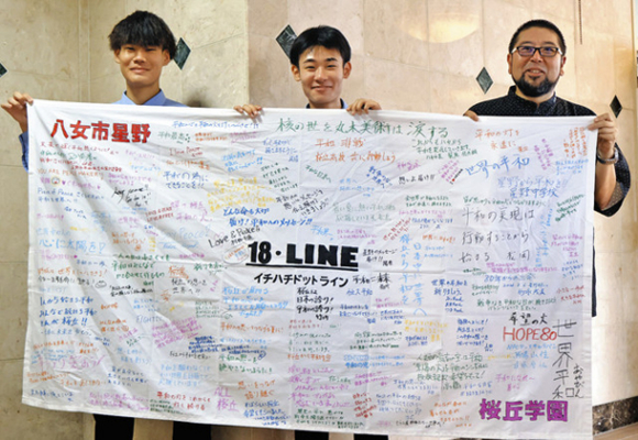 残り火を守る関係者からのメッセージが書き込まれた横断幕を掲げる生徒ら＝豊橋市の桜丘学園で