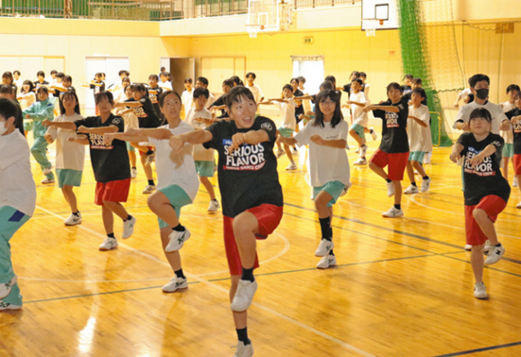 三重高ダンス部の部員と一緒に踊る生徒たち＝松阪市中部中で