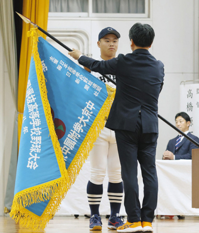 伊藤校長(手前)から選抜旗を渡される主将=名古屋市昭和区で