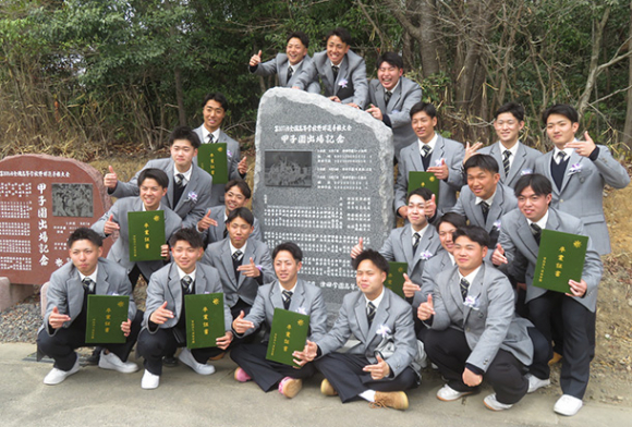 昨夏の甲子園出場の記念碑で集合写真を撮る津田学園高の３年生たち＝桑名市野田の同高野球場で