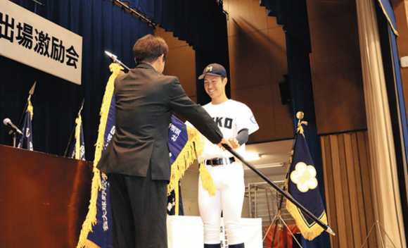 神崎校長(手前)から選抜旗を受け取る大西主将=松阪市久保町の三重高で