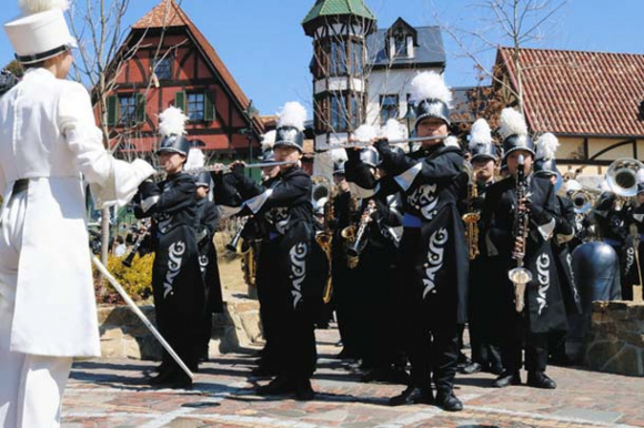 青空の下で街並みに合わせた音色を奏でる部員ら＝長久手市のジブリパークで