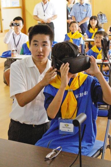 愛工大名電高生のサポートを受けながらVRのゴーグルを着用し、教材を体験する子ども=大口町の大口北小で