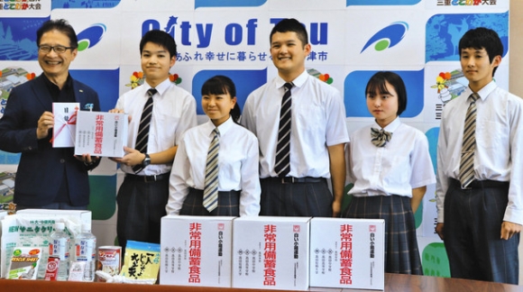 白い小箱（非常用備蓄食品）を寄贈した高田学苑の生徒ら＝津市役所で