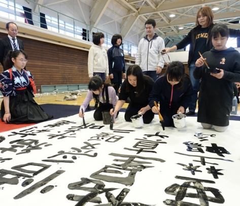 高校生に習いながら書を仕上げる児童ら=笠松町下羽栗小で