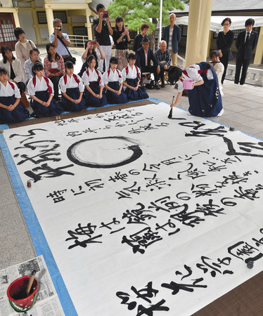 平和を祈り、揮毫する桜花学園高書道部の生徒たち=中区の県護国神社で