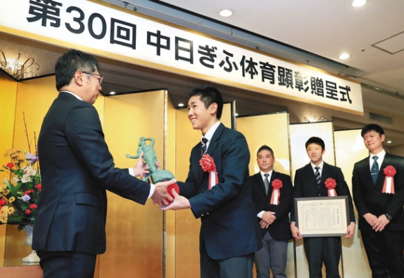 贈呈式で、大島宇一郎社長(左)から「勝利の女神像」を受け取る中京学院大中京高の村瀬仁紀前主将=21日午前、岐阜市の岐阜グランドホテルで