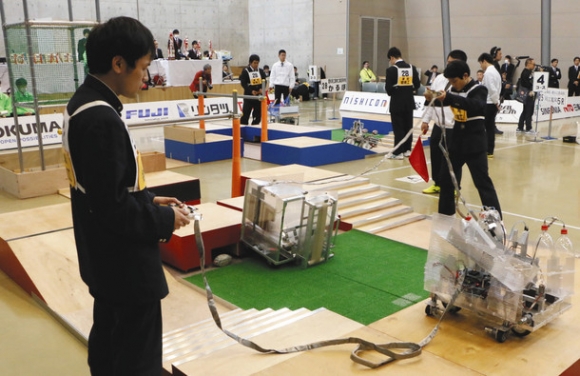 ロボットをキックエリアへ移動させたり、スクラムに見立ててロボットで木箱を押したりする高校生たち＝刈谷市産業振興センターで