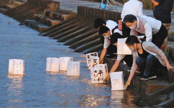 灯籠を豊川に流す集会参加者=豊橋市湊町で