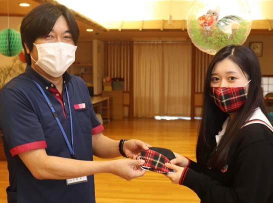 施設長の高橋さん(左)にマスクを手渡す生徒会長の女子生徒=豊田市大清水町の第2とよた苑で