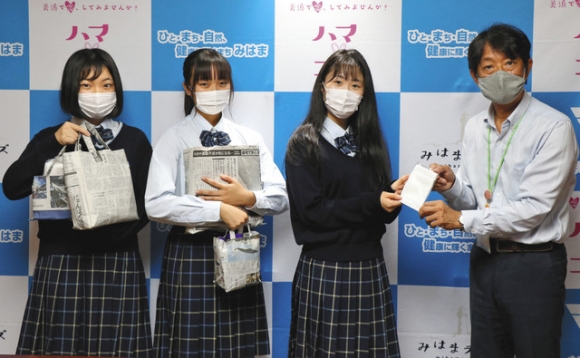 八谷副町長(右)に集めたマスクを手渡す(左から)岡本さん、筒井さん、仲野さん=美浜町役場で