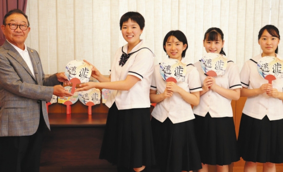 加納会長(左)にうちわを手渡す女子生徒(左から2人目)ら=多治見市音羽町の多治見市医師会館で
