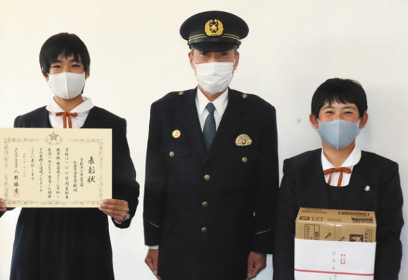 八野署長(中)から記念品のチョコレートや賞状を受け取った原さん(左)と岡谷さん=瀬戸市せいれい町の聖霊中・高で
