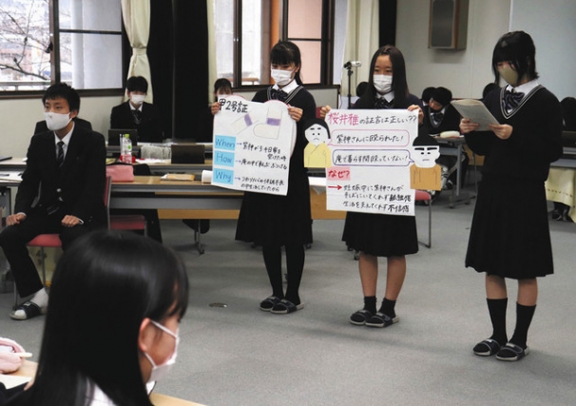 主張をまとめた紙を掲げて主張を述べる弁護人役の生徒たち＝多治見市の多治見西高で