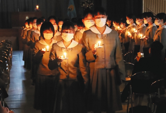 「世の光になるように」との願いを込めたろうそくの明かりを手に退場する卒業生＝岐阜市の聖マリア女学院高で