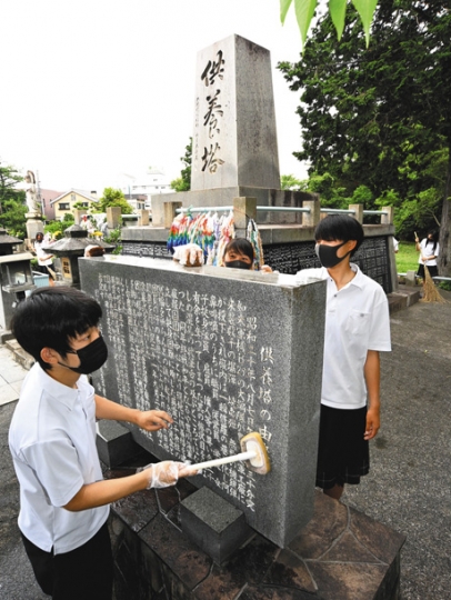 大空襲の供養塔を清掃する豊川高の生徒たち。左は生徒会長の鈴木さん=7日、愛知県豊川市で(太田朗子撮影)