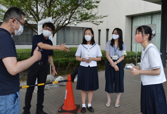 新型コロナワクチン集団接種会場で検温作業を体験する長谷川さん(右)、竹内さん(右から3人目)と近藤市長(同4人目)=日進市栄5のトヨタ自動車日進研修センターで