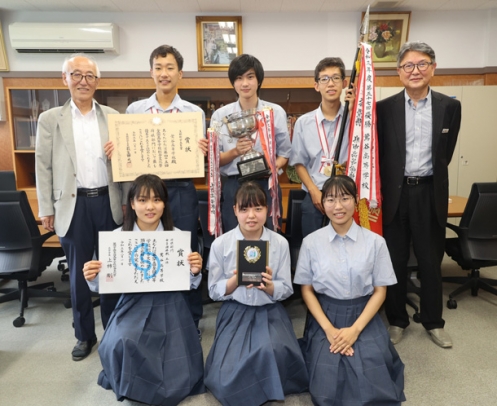 全国高校将棋選手権大会で優勝した男子団体の３人（後列左から２～４人目）。女子団体の生徒たちも健闘した＝岐阜市の鶯谷高で